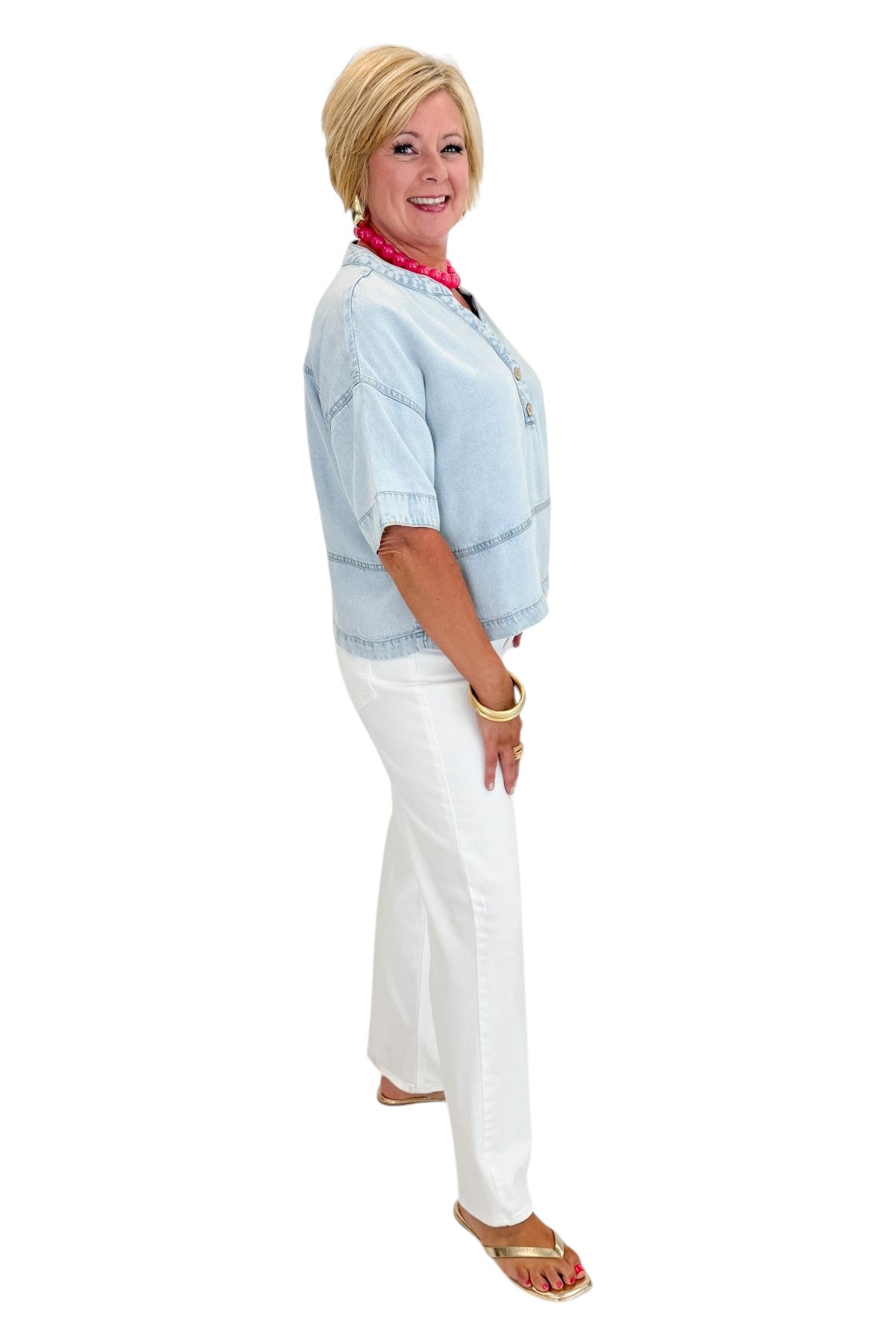 Side view of woman wearing Swagger Boutique’s Light Wash Denim V-Neck Top with jeans against white studio background.