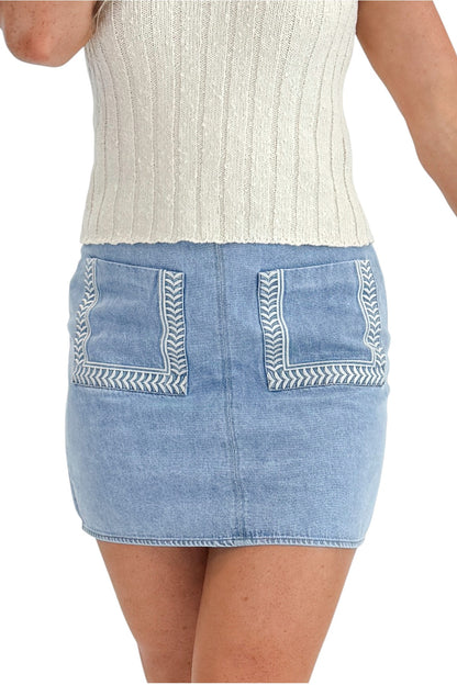 Front detail view of woman wearing Swagger Boutique’s Light Wash Embroidered Pocket Skirt with sweater against white studio background.