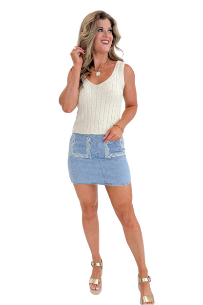 Front view of woman wearing Swagger Boutique’s Light Wash Embroidered Pocket Skirt with sweater against white studio background.