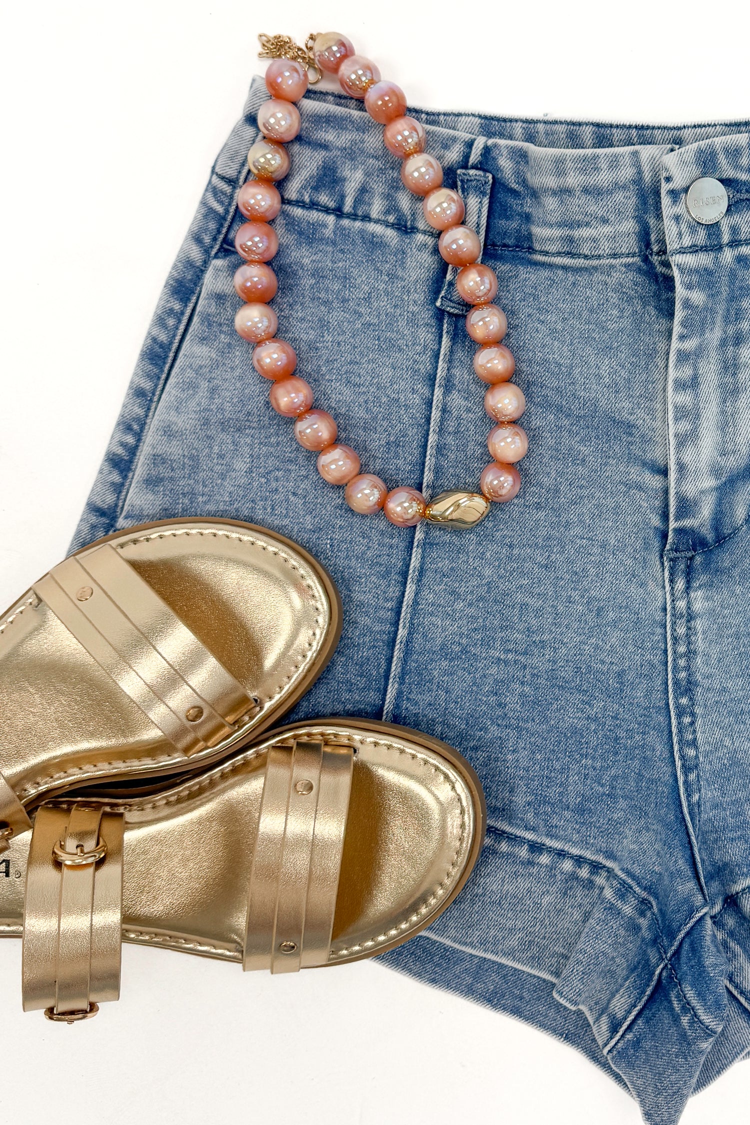 Swagger Boutique’s Light Wash Seamed Denim Shorts with sandals and necklace against white studio background.