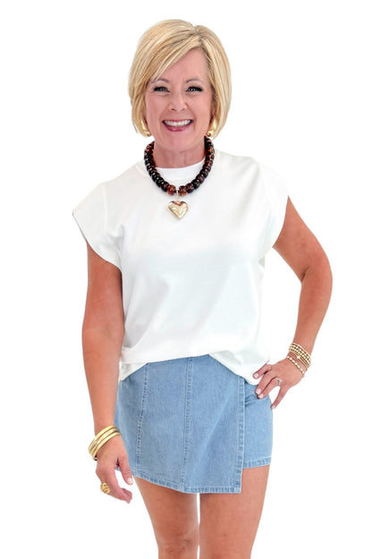 Front view of woman wearing Light Wash Denim Wrap Skort with white top against white studio background.