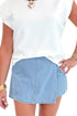 Front detail view of woman wearing Light Wash Denim Wrap Skort with white top against white studio background.