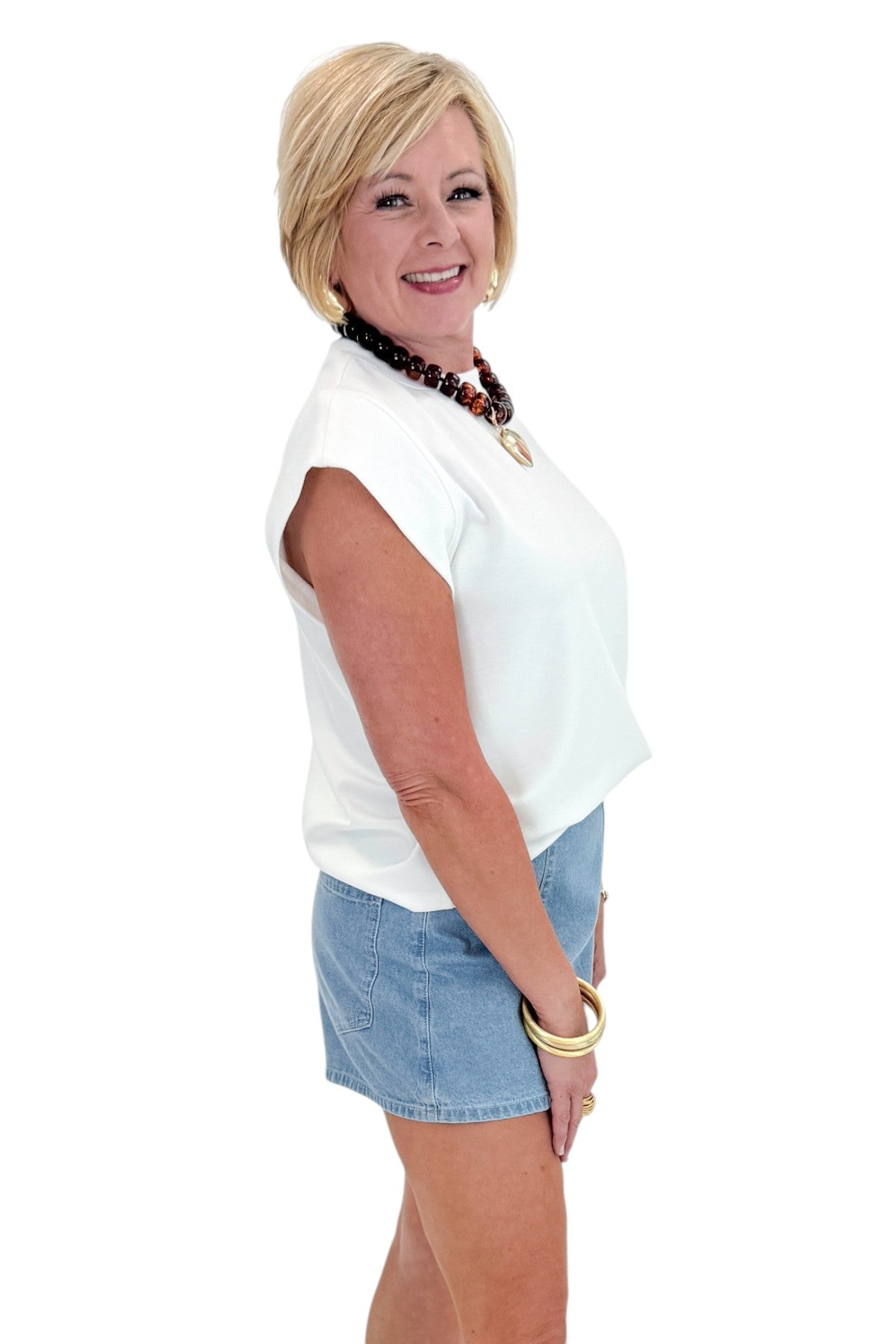 Side view of woman wearing Light Wash Denim Wrap Skort with white top against white studio background.