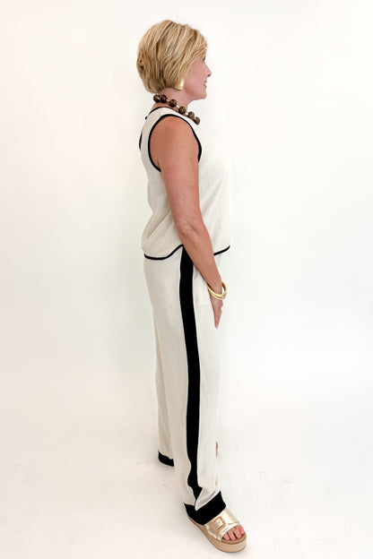 Side view of woman wearing Swagger Boutique’s Linen &amp; Black Lined Tank with matching Linen &amp; Black Stripe Pants against white studio background.