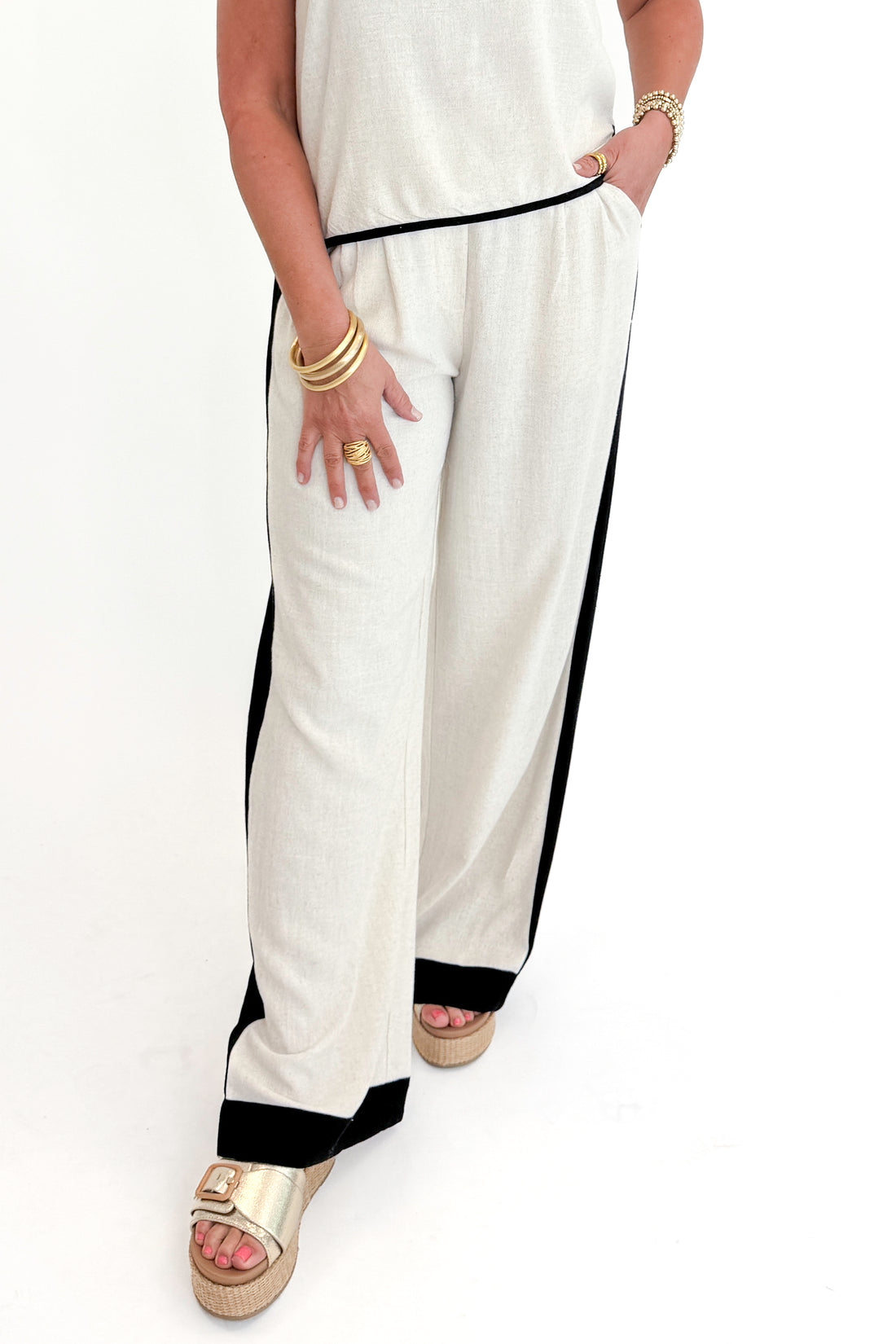 Front detail view of woman wearing Swagger Boutique’s Linen &amp; Black Lined Tank with matching Linen &amp; Black Stripe Pants against white studio background.