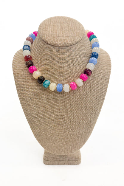 Colorful beaded necklace on a beige mannequin bust against a white background