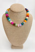 Colorful beaded necklace on a beige jewelry display bust against a white background