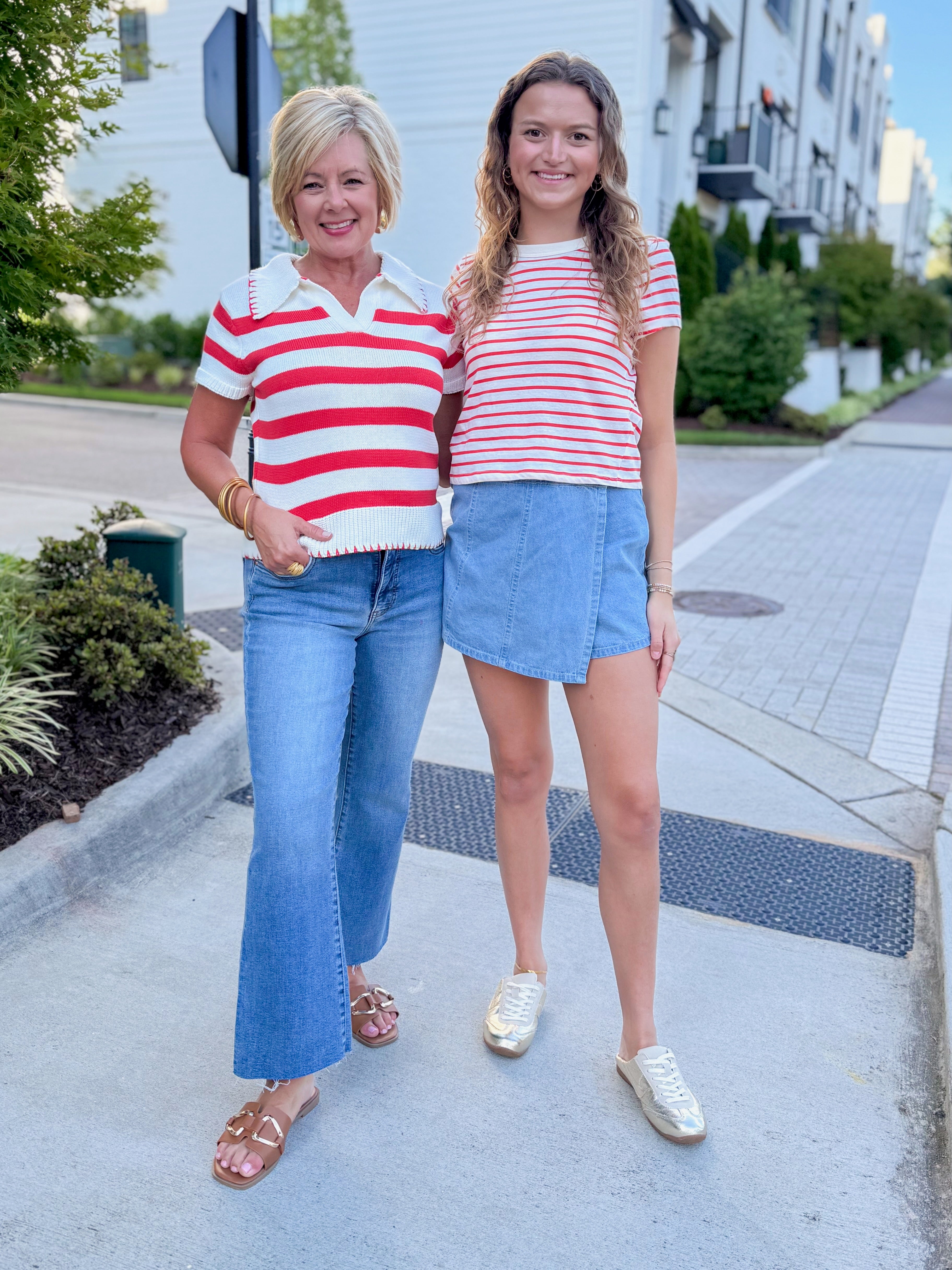 Front view of woman wearing Swagger Boutique’s Lychee Junie Striped Tee by Z Supply with Light Wash Denim Wrap Skort and woman wearing Cream &amp; Coral Striped Knit Top with jeans walking outside at a city.