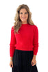 Front view of woman wearing Red Mock Neck Eyelash Sweater with black skirt against white studio background.