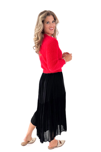 Side view of woman wearing Red Mock Neck Eyelash Sweater with black skirt against white studio background.