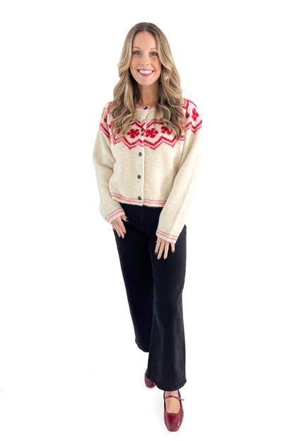 Front view of woman wearing Ivory &amp; Red Faie Isle Button Up Cardigan with jeans against white studio background.
