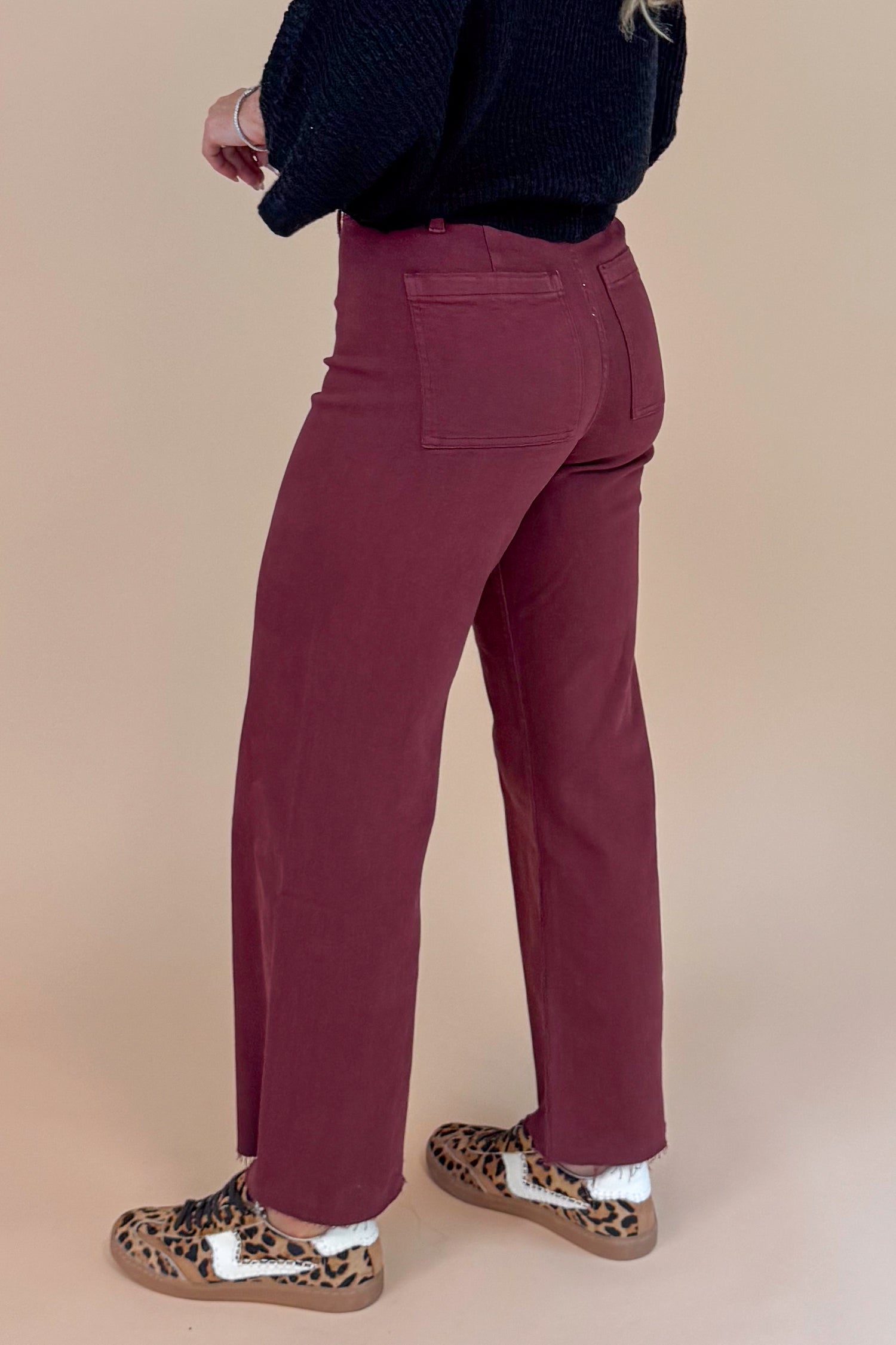Person wearing maroon pants with a neutral background