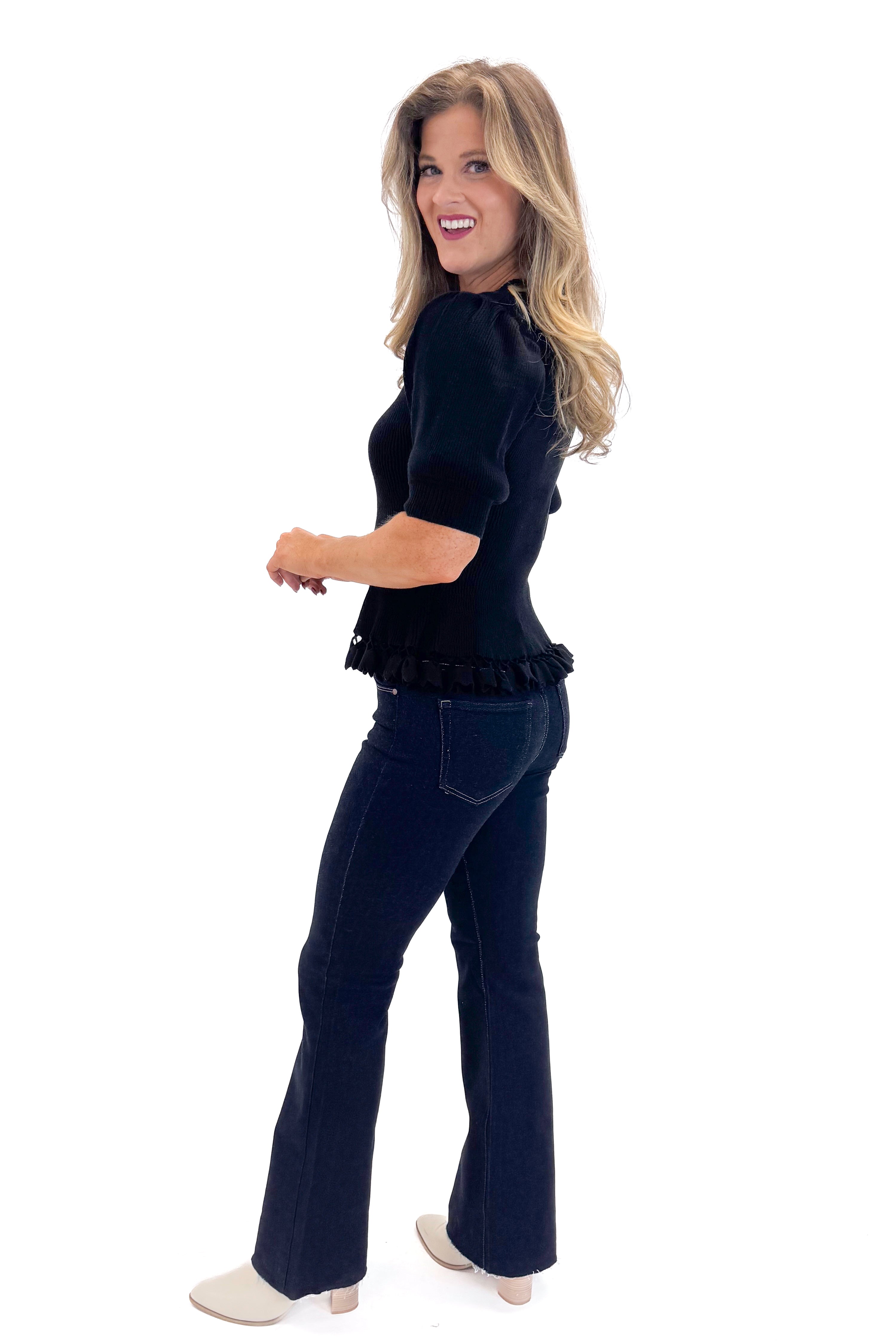 Side view of woman wearing Black Ribbed Trim Detail Top with jeans against white studio background.