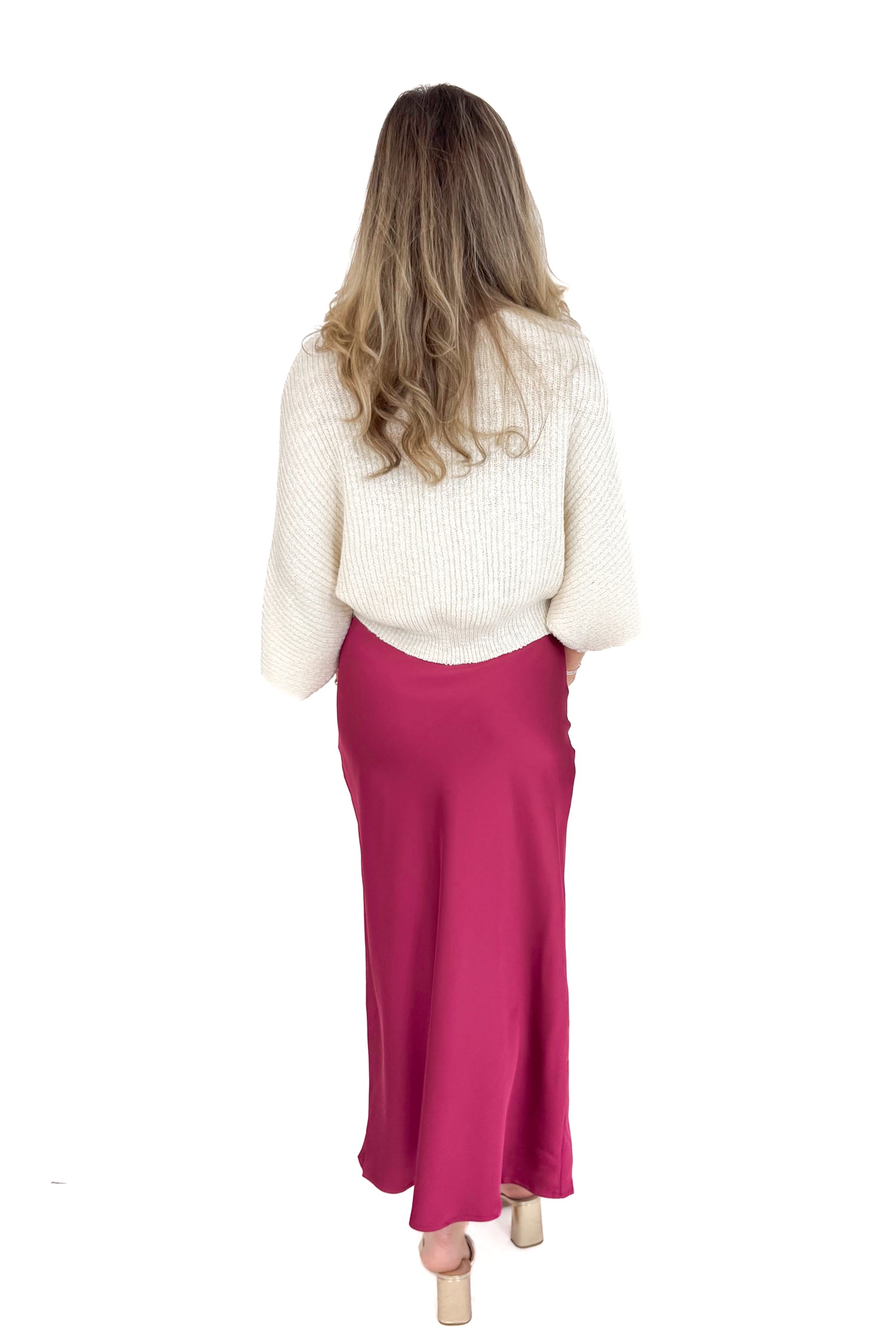 Person wearing a white sweater and burgundy skirt on a white background