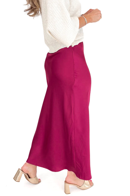 Person wearing a burgundy skirt and white sweater on a white background