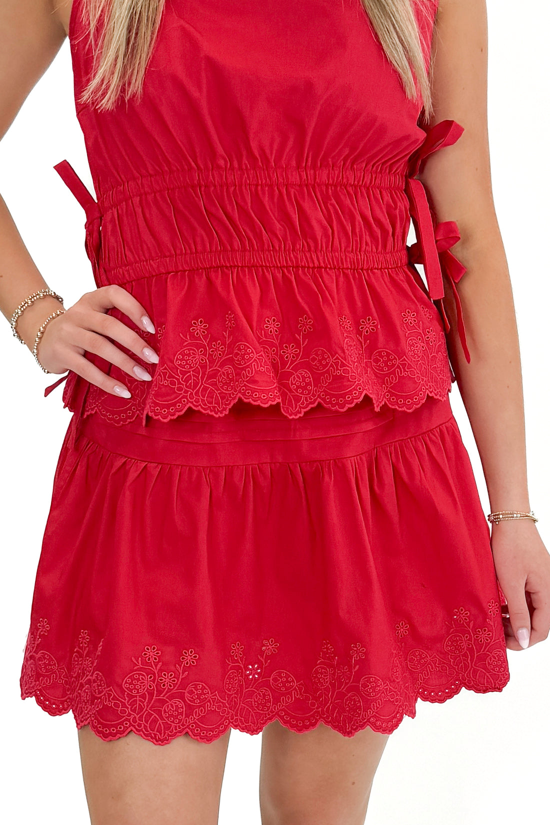 Front view of woman wearing Red Eyelet Hem Skirt with matching top against white studio background.