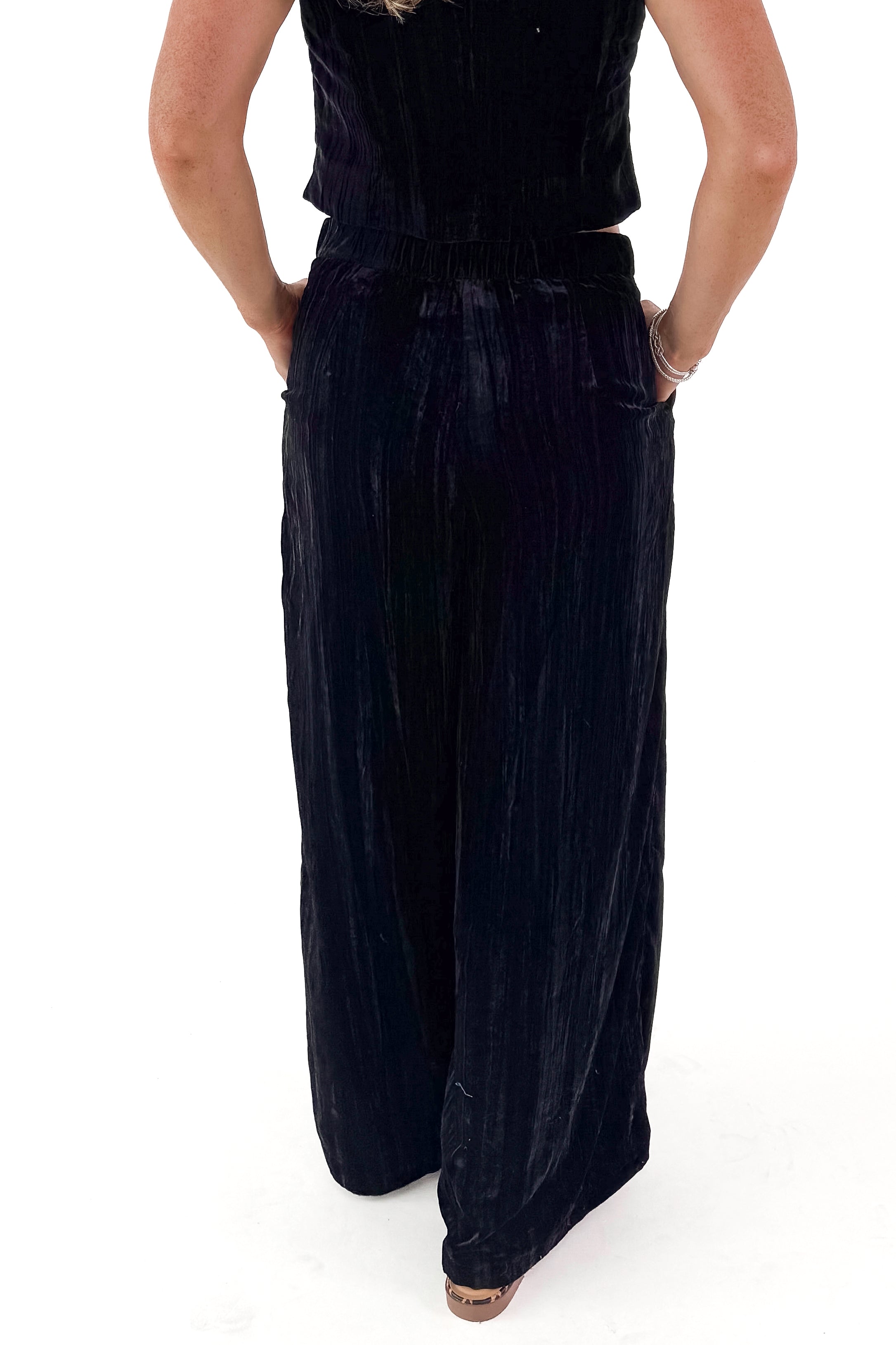 Back view of woman wearing Black Textured Velvet Wide Leg Pants and matching tank against white studio background.