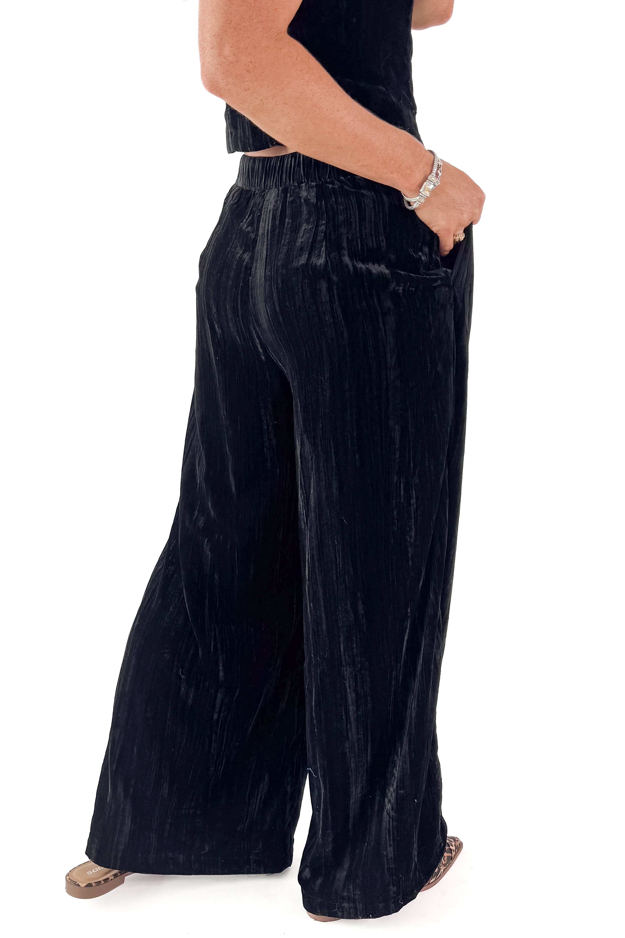 Side detailed view of woman wearing Black Textured Velvet Wide Leg Pants and matching tank against white studio background.