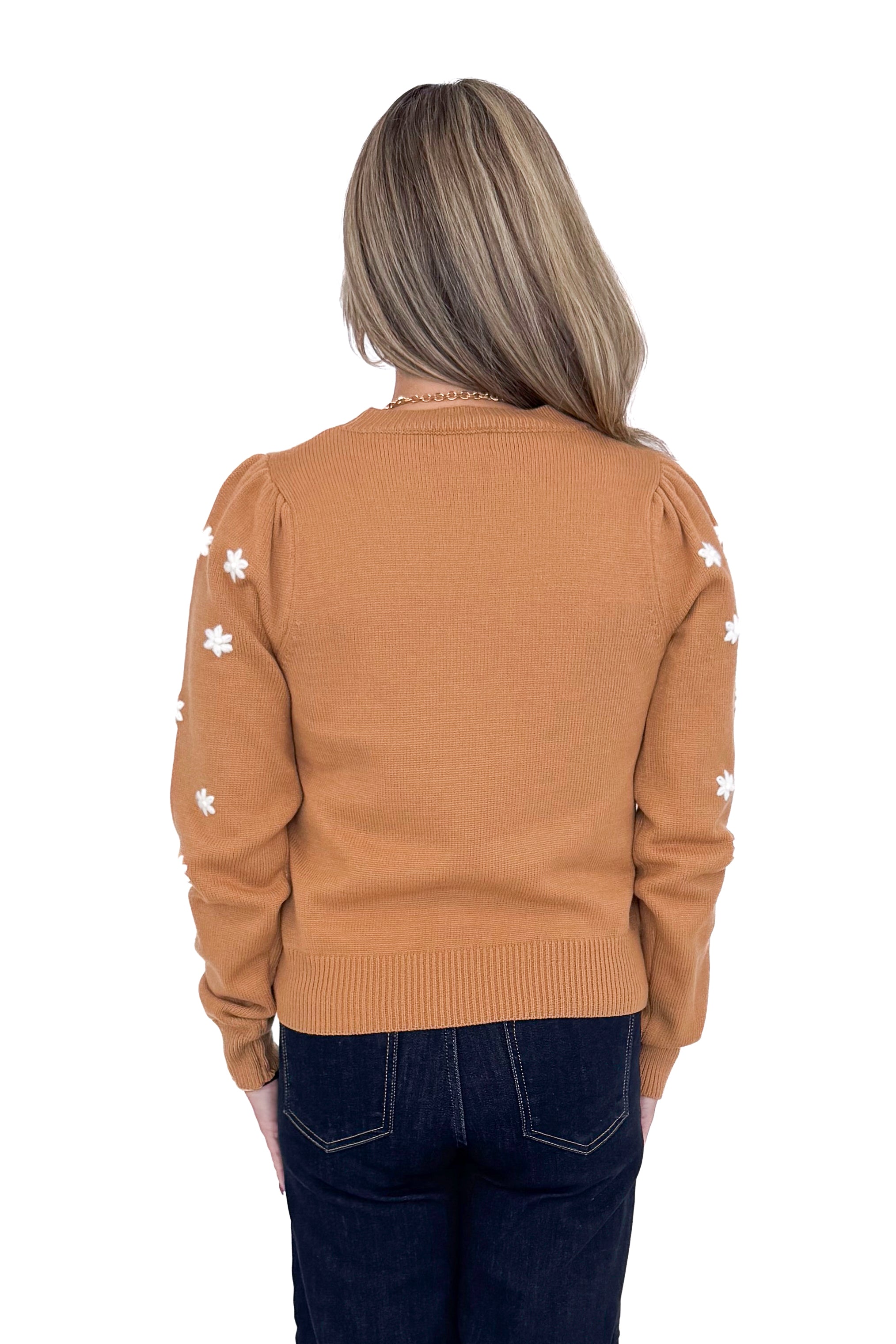 Back view of Woman in studio wearing Taupe With Embroidered Floral Sleeve Sweater and blue jeans with white background. 