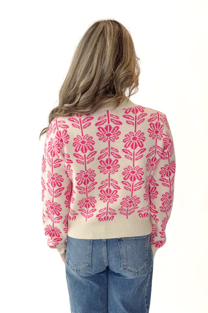 Back view of woman wearing Cream and Pink Floral Patterned Sweater with jeans against white studio background. 