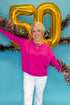 Front view of woman wearing Magenta Center Seam Sweater with jeans against blue background.