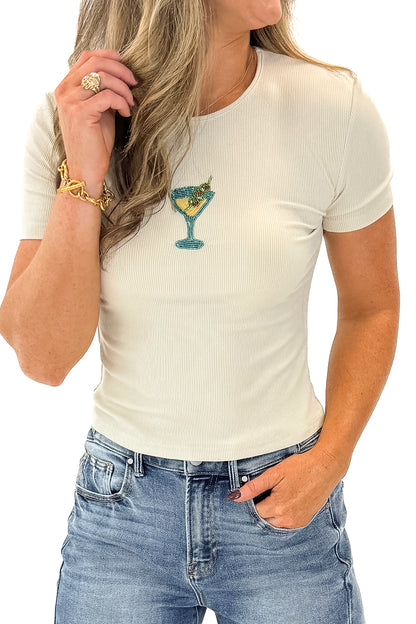 Front detail view of woman wearing Cream Martini Beaded Ribbed Top with jeans against white studio background.