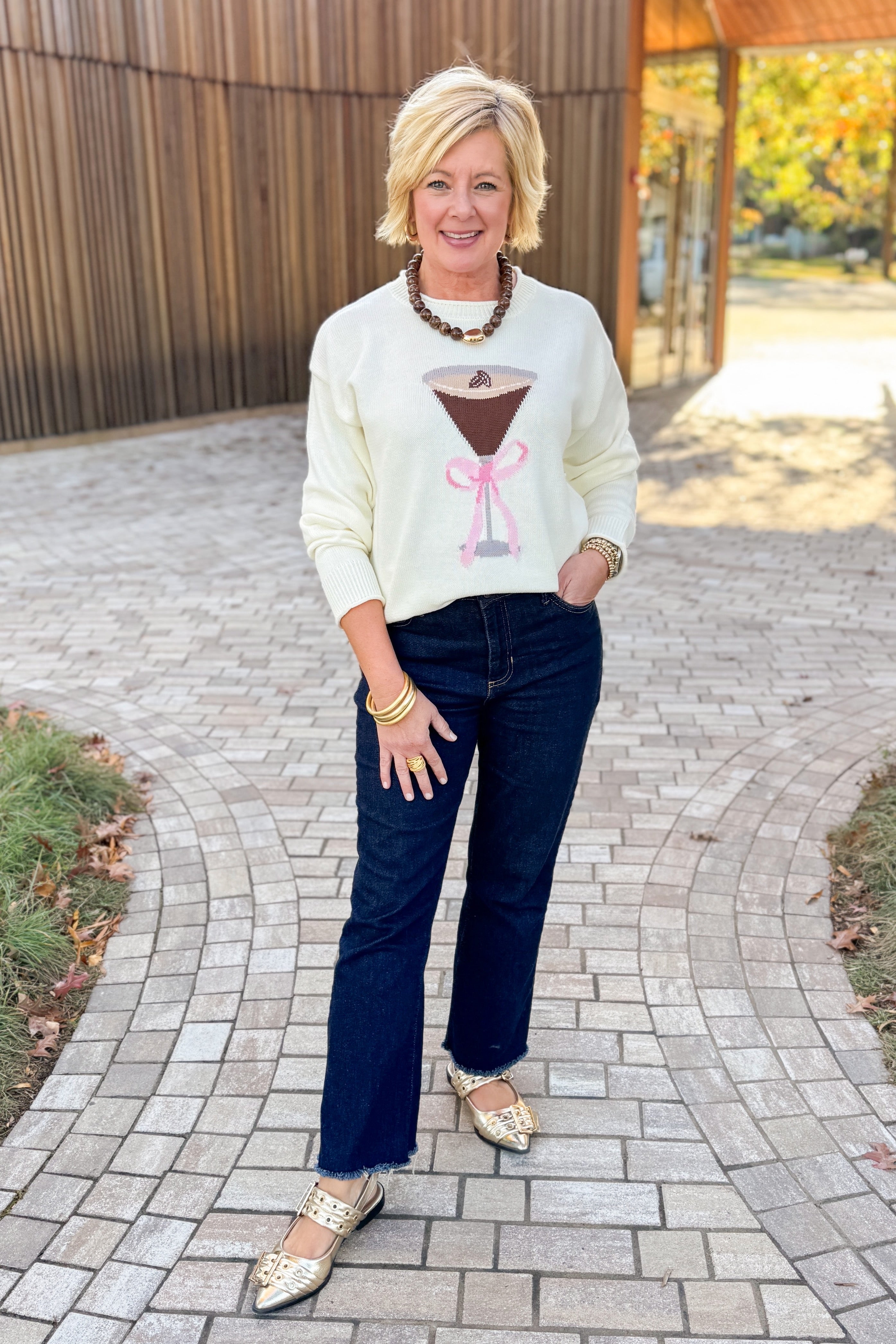Front view of woman wearing White Espresso Martini With Bow Sweater with jeans outside.