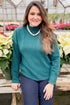 Front view of woman wearing Green Mock Neck Sweater with jeans with holiday decor.