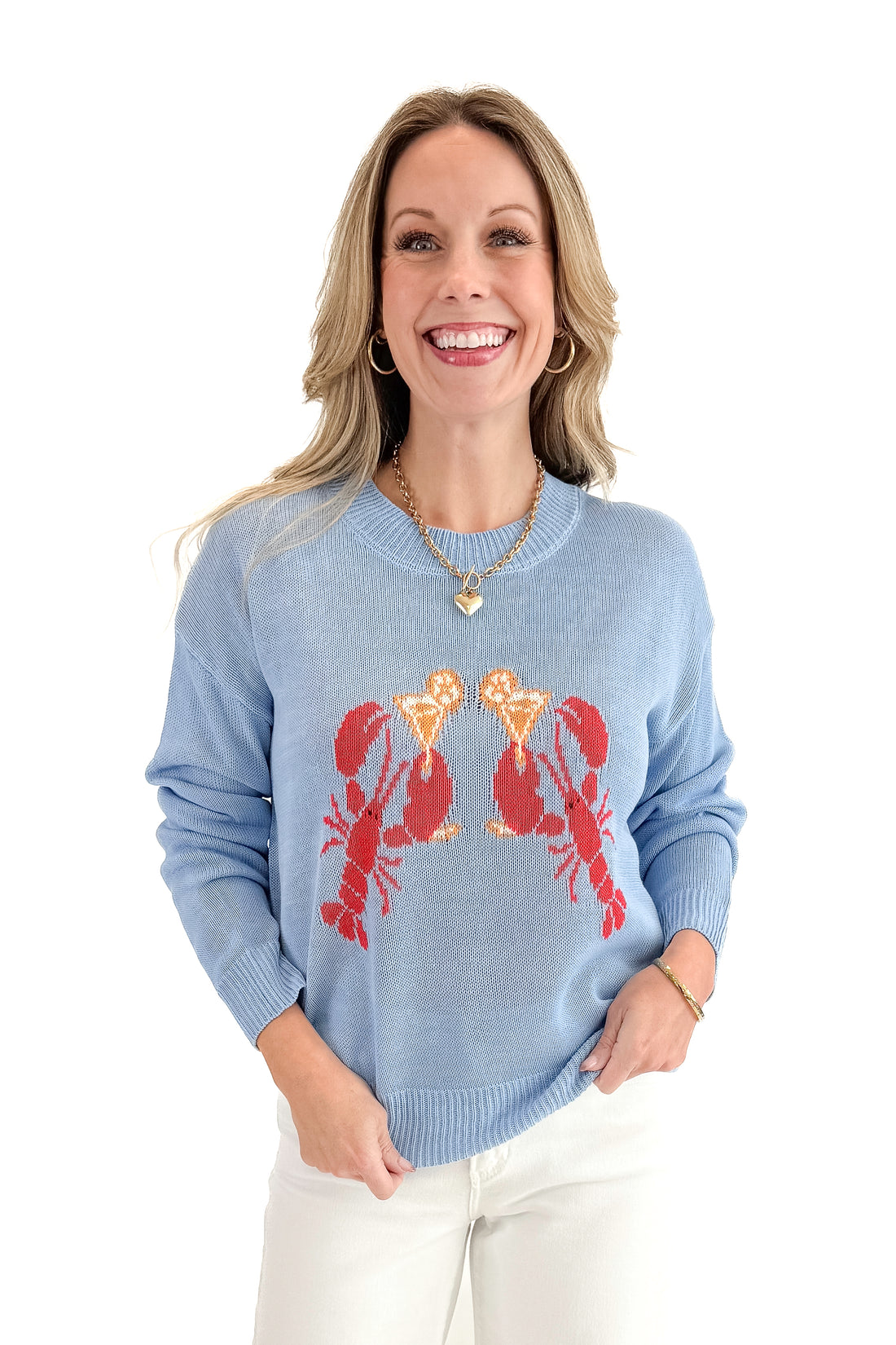 Front view of woman wearing Blue Lobster Graphic Sweater with jeans against white studio background.