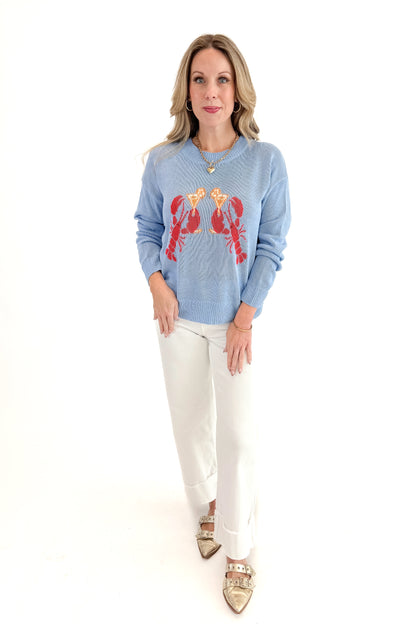 Front view of woman wearing Blue Lobster Graphic Sweater with jeans against white studio background.