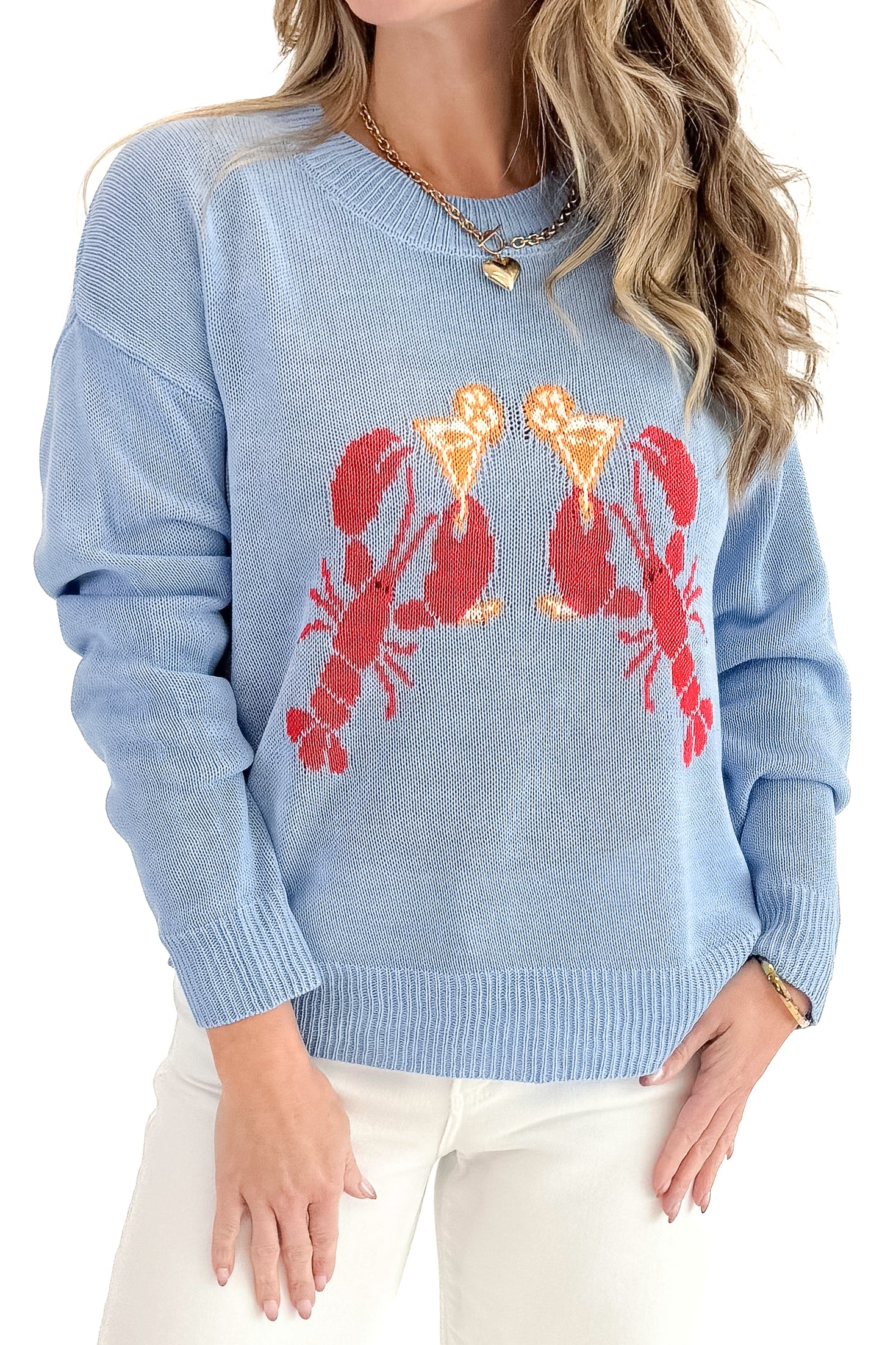 Front detail view of woman wearing Blue Lobster Graphic Sweater with jeans against white studio background.