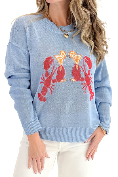 Front detail view of woman wearing Blue Lobster Graphic Sweater with jeans against white studio background.