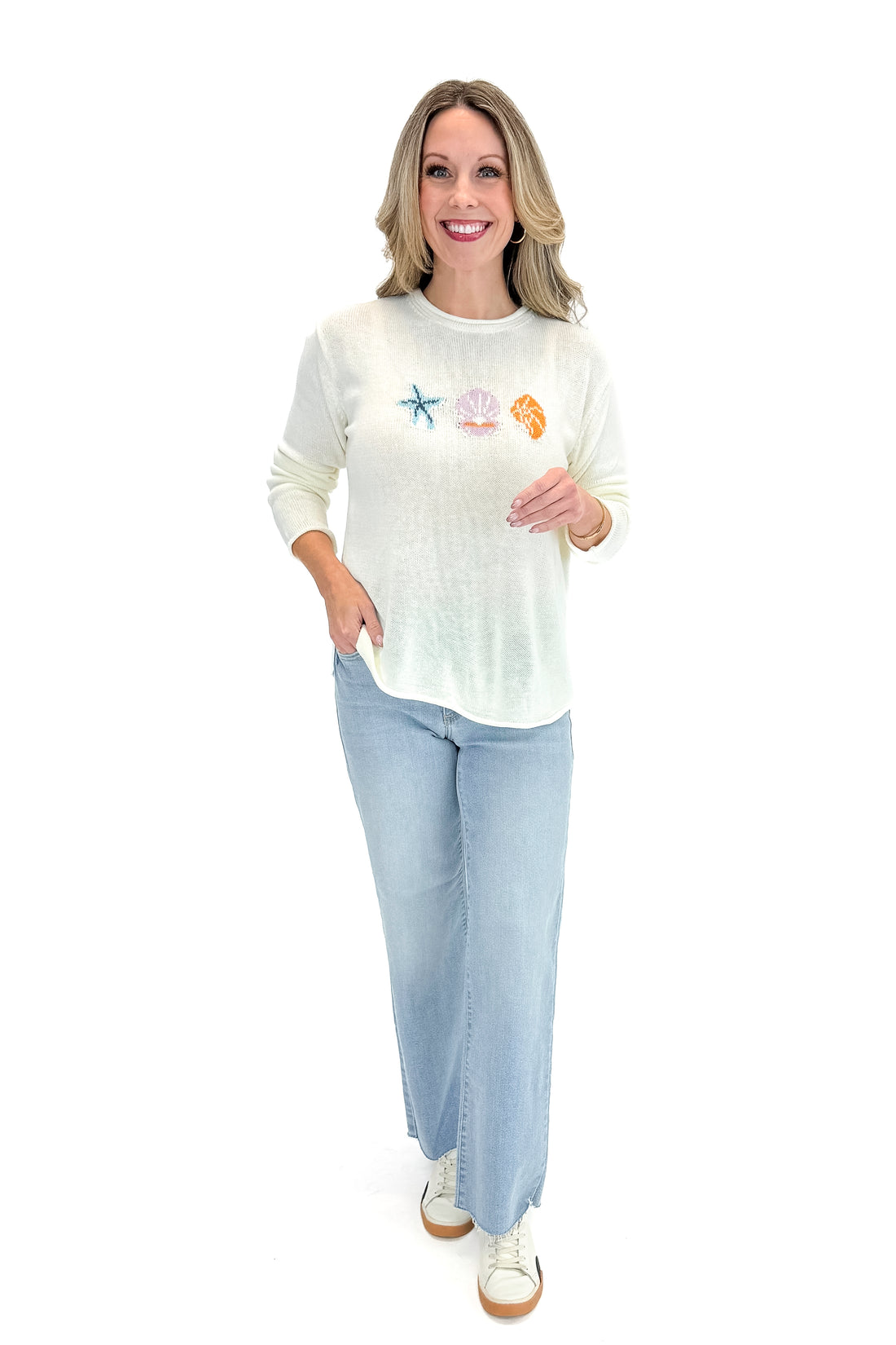 Front view of woman wearing Cream Lightweight Shell Print Sweater with jeans against white studio background.