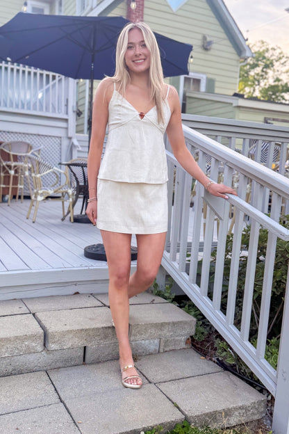 Front view of woman wearing Linen Bead Detail Top with matching Linen Mini Skirt walking outside at a restaurant.