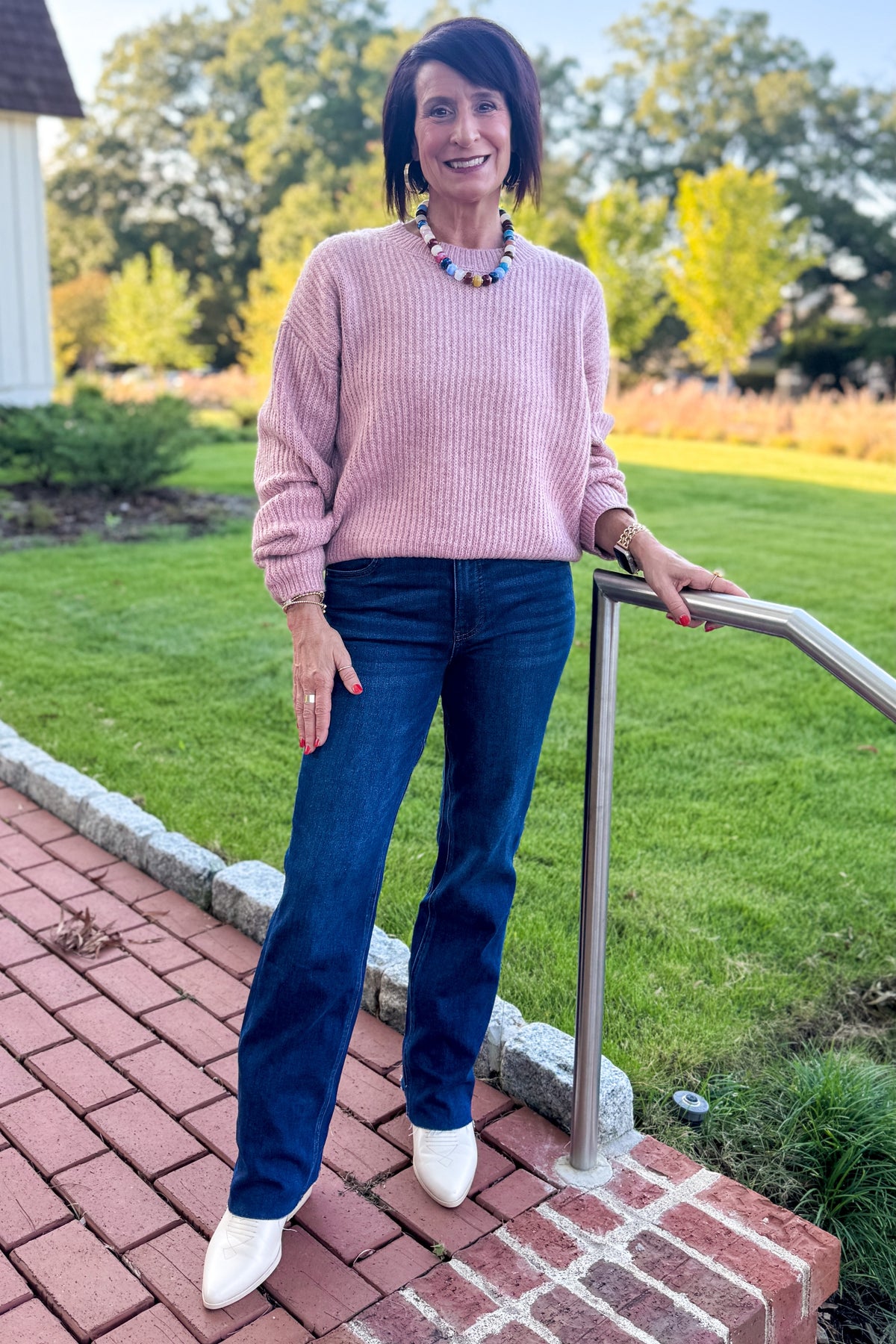 Front view of woman wearing Swagger Boutique’s Mauve Ribbed sweater with jeans standing outside on a brick walkway.
