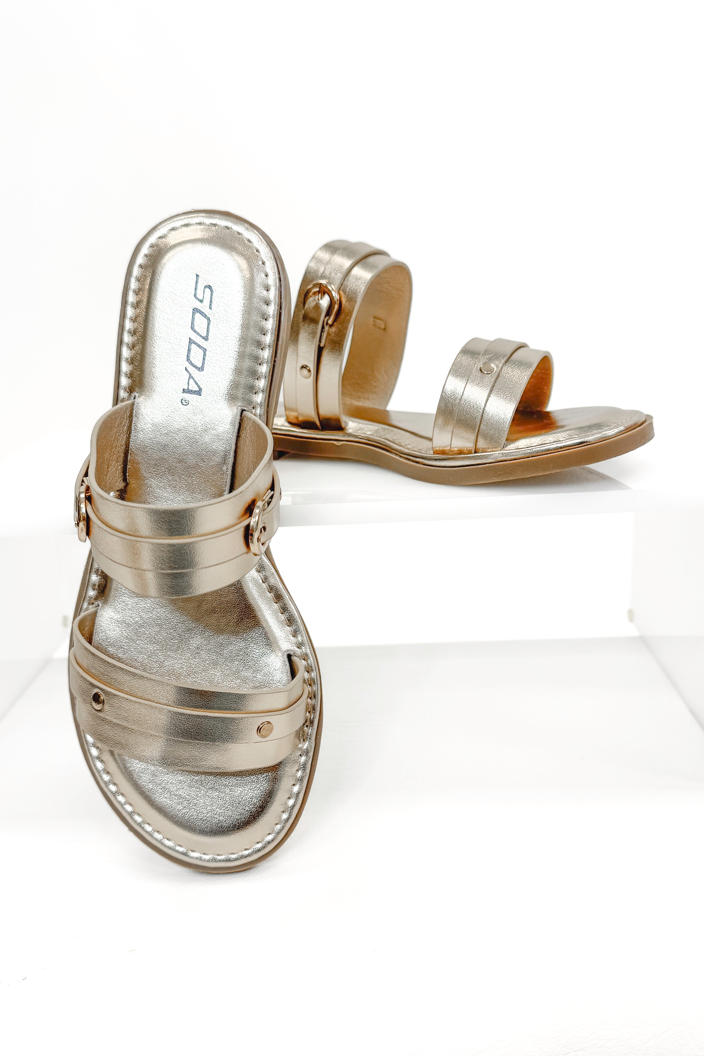 Maya- Gold Double Strap Buckle Detail Sandals against white studio background