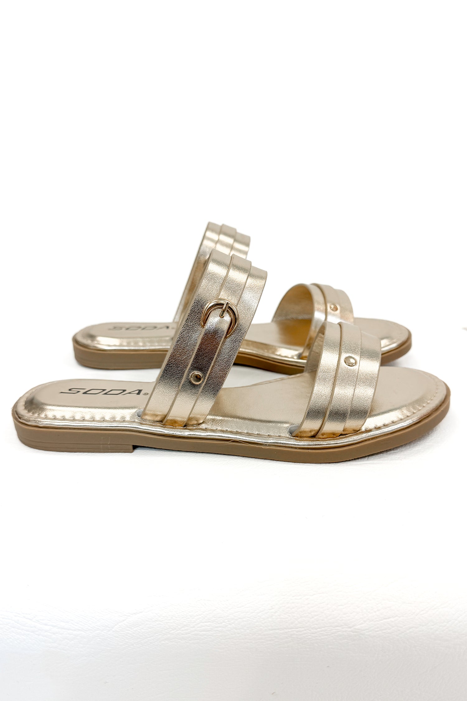 Maya- Gold Double Strap Buckle Detail Sandals against white studio background