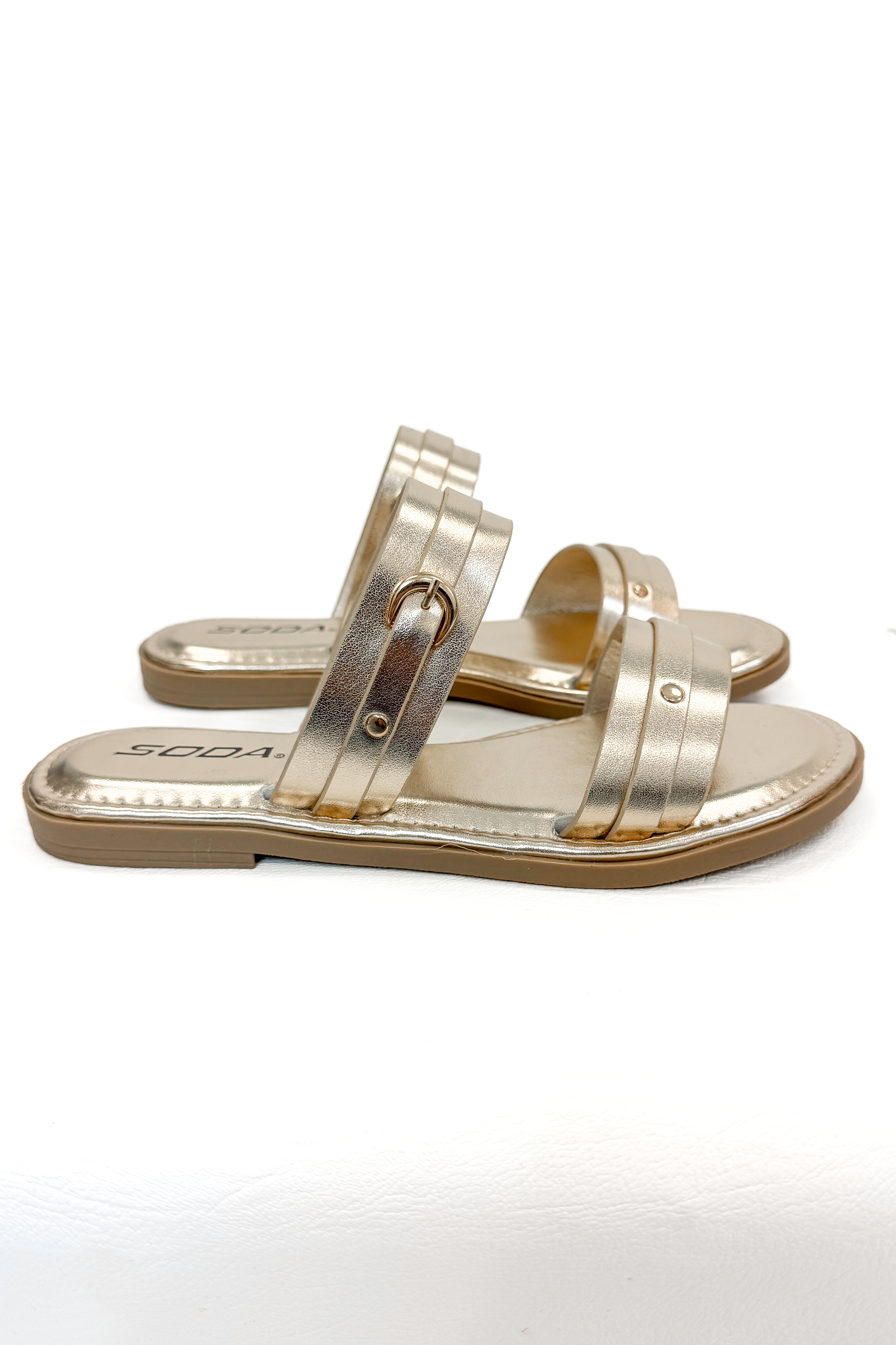 Maya- Gold Double Strap Buckle Detail Sandals against white studio background