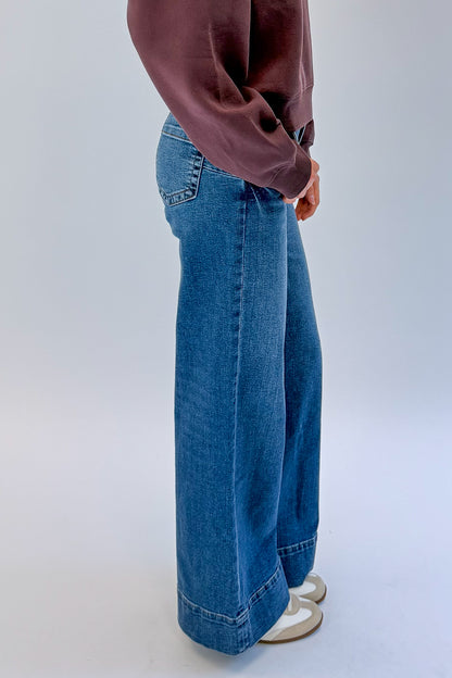 Side view of woman wearing Swagger Boutique’s Maya Wide Leg Jeans In Medium Wash- Journey by Kut from the Kloth against white studio background.