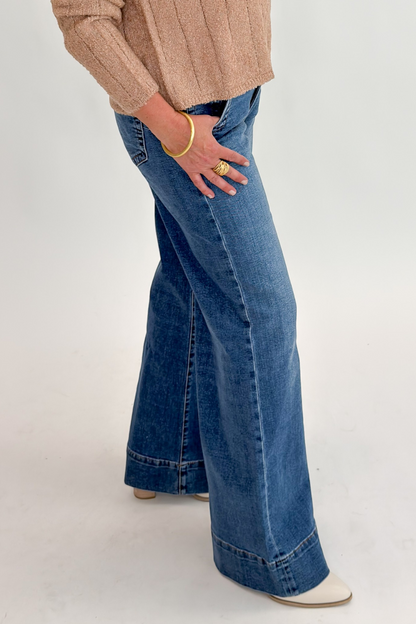 Side detail view of woman wearing Swagger Boutique’s Maya Wide Leg Jeans In Medium Wash- Journey by Kut from the Kloth against white studio background.