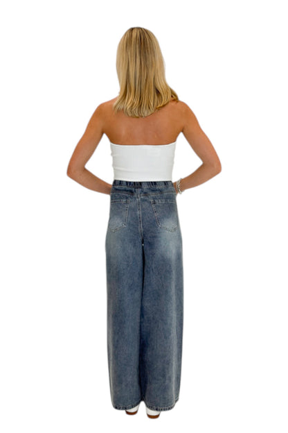 Back view of woman wearing Swagger Boutique’s Medium Wash Brown Stripe Detail Jeans against white studio background.