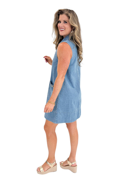 Side view of woman wearing Swagger Boutique’s Medium Wash Sleeveless Denim Midi Dress by Entro with sandals against white studio background.