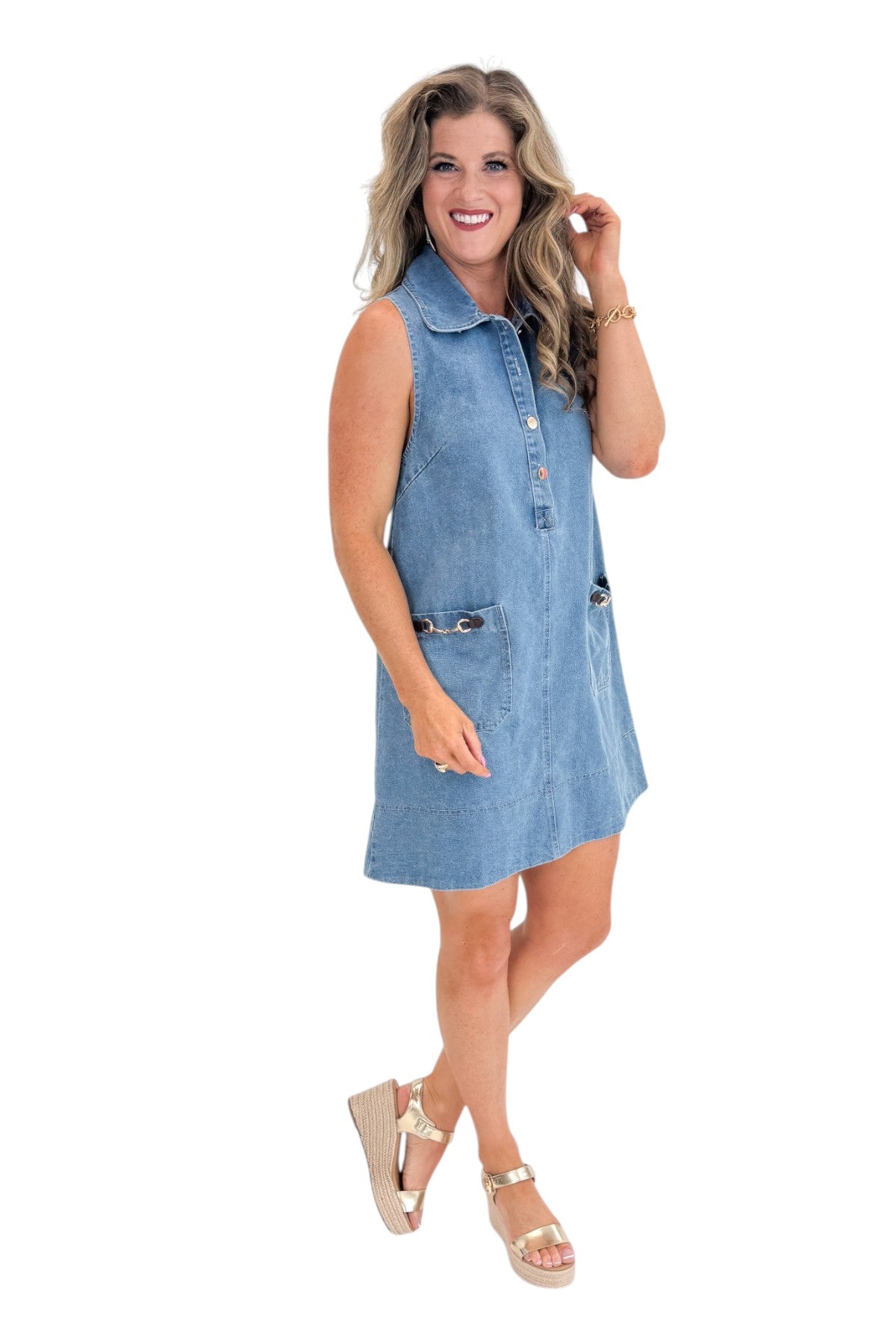 Side view of woman wearing Swagger Boutique’s Medium Wash Sleeveless Denim Midi Dress by Entro with sandals against white studio background.
