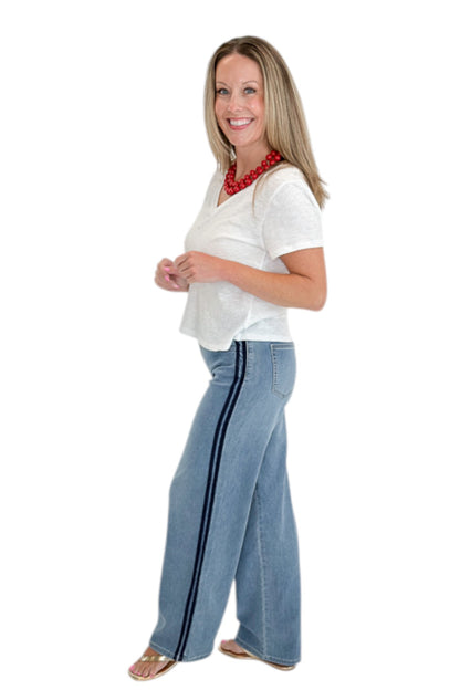 Side view of woman wearing Swagger Boutique’s Medium Wash Tuxedo Stripe Jeans by Just Black Denim with white top against white studio background.