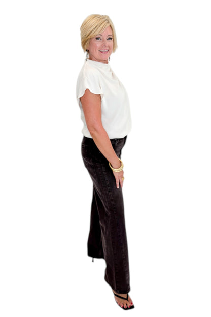 Side view of woman wearing Swagger Boutique’s Meg Wide Leg Jeans in Chocolate by Kut from the Kloth with top against white studio background.