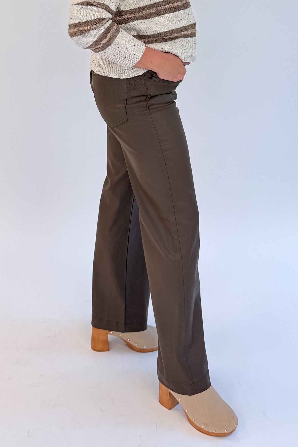 Side view of woman wearing Swagger Boutique’s sweater with Meg Coated Wide Leg Jeans in Toffee by Kut from the Kloth against white studio background.