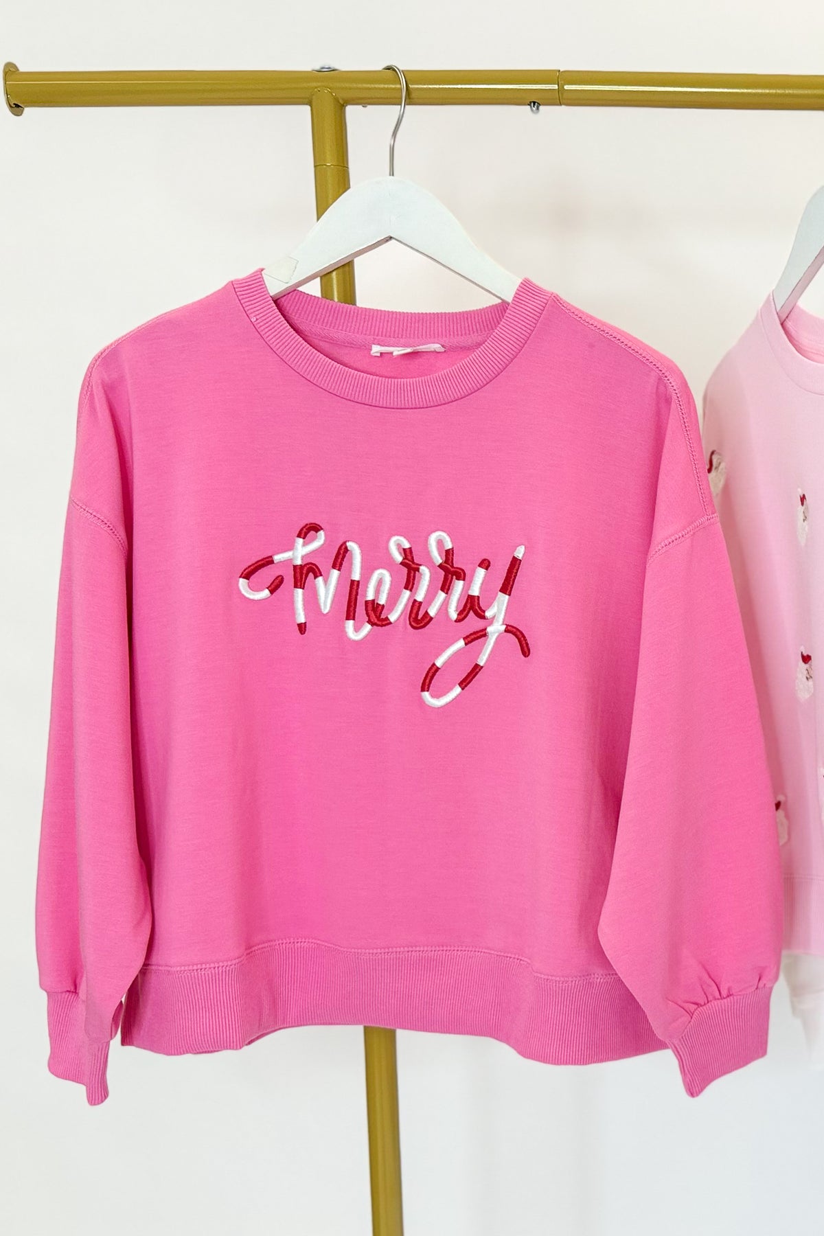 Millie Merry Corded Holiday Sweatshirt hanging on a rack against a white background.