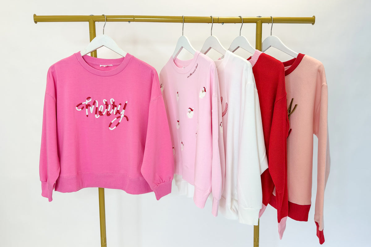 Holiday Sweatshirts hanging on a rack against a white background.