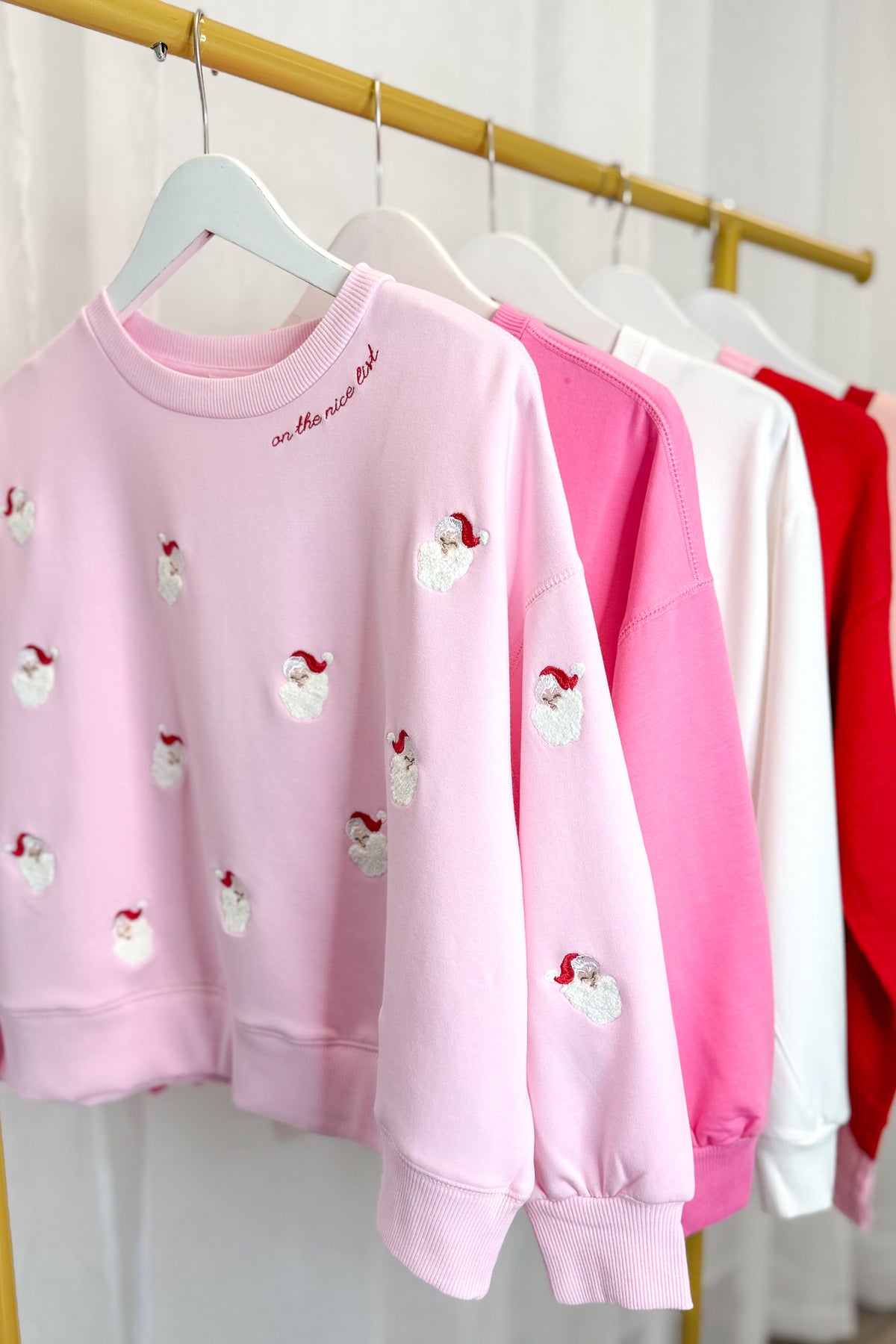 Millie Small Santas Sweatshirt hanging on a rack.