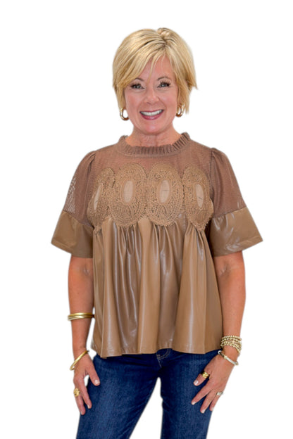 Front view of woman wearing Swagger Boutique’s Mocha Lace Applique Faux Leather Top with jeans against white studio background.